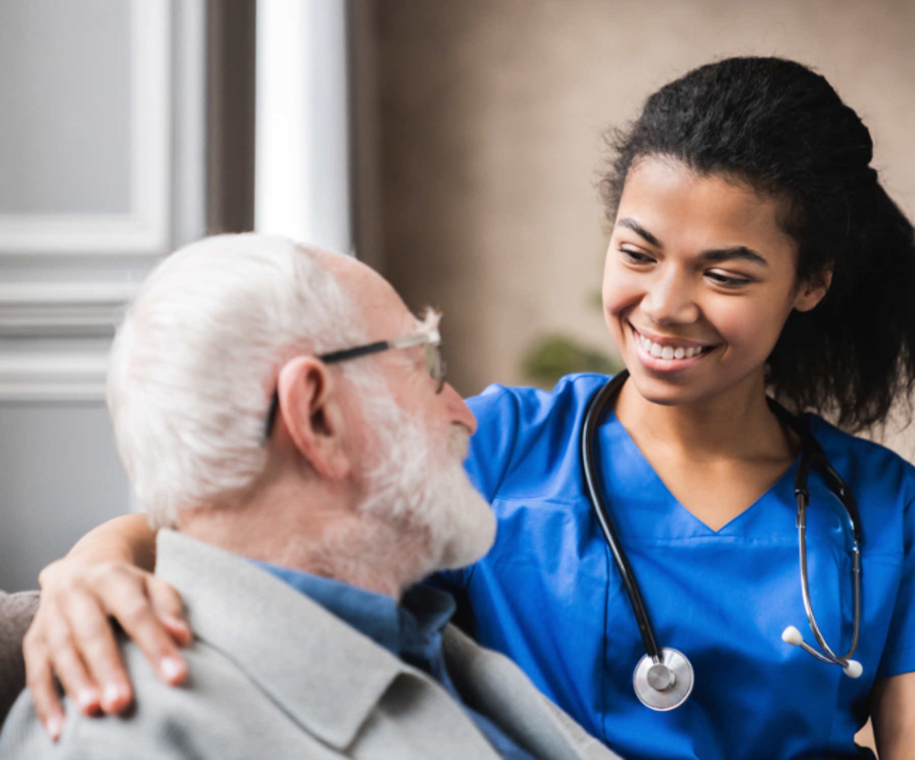Smiling healthcare professional with arm around the shoulder of an older adult patient.